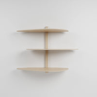 Étagère murale modulaire en bois clair à trois niveaux pour plantes, fixée sur un support central vertical.